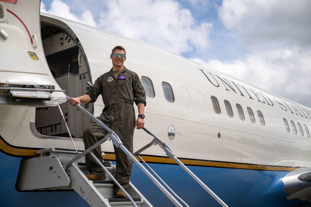 Pilot stands on plane stairs.