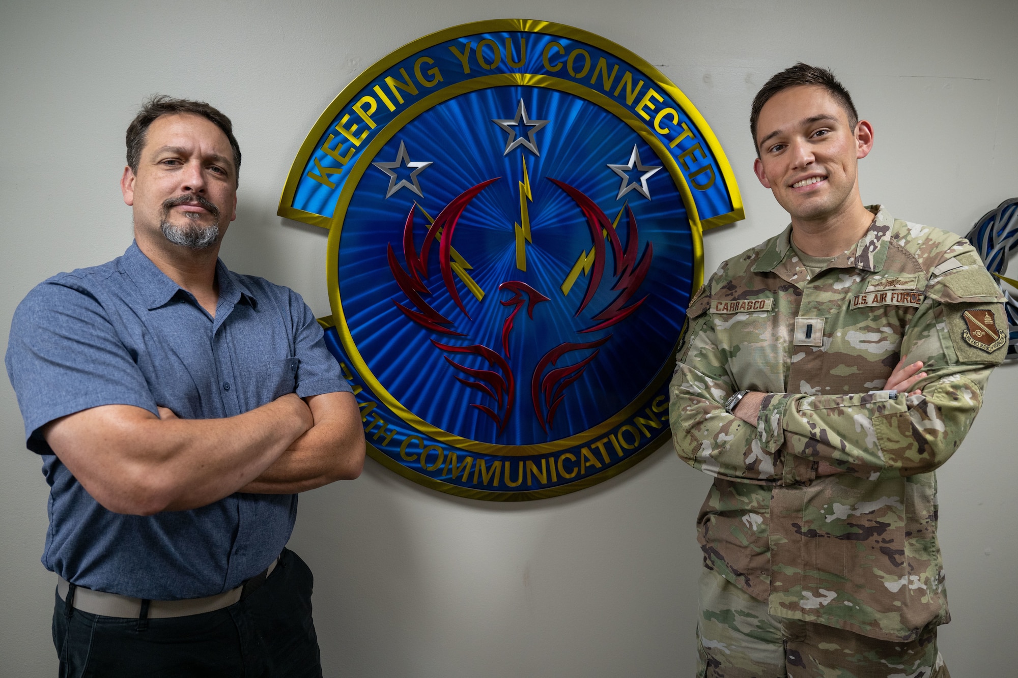 People stand in front of squadron insignia.