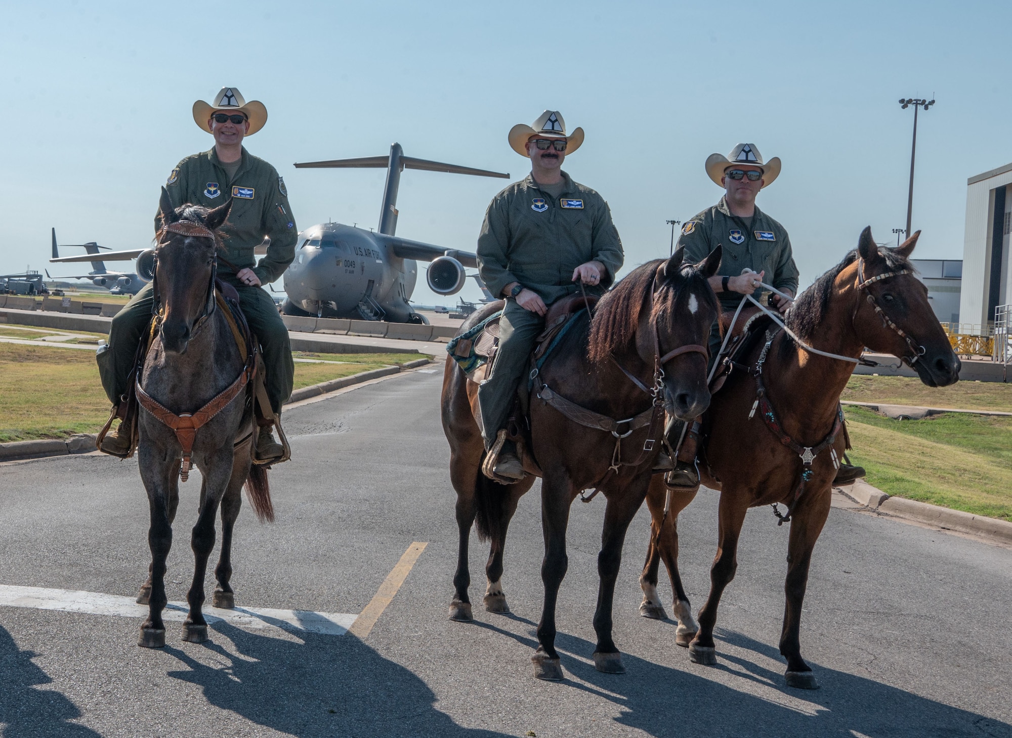 97th Air Mobility Wing leadership pauses for a photo in front of a C-17 Globemaster III during the 27th Annual Cattle Drive at Altus Air Force Base, Oklahoma, Aug. 21, 2025. Wing leaders and community members guided cattle around Altus AFB on horseback as part of the annual tradition. (U.S. Air Force photo by Tech. Sgt. Hailey Haux)