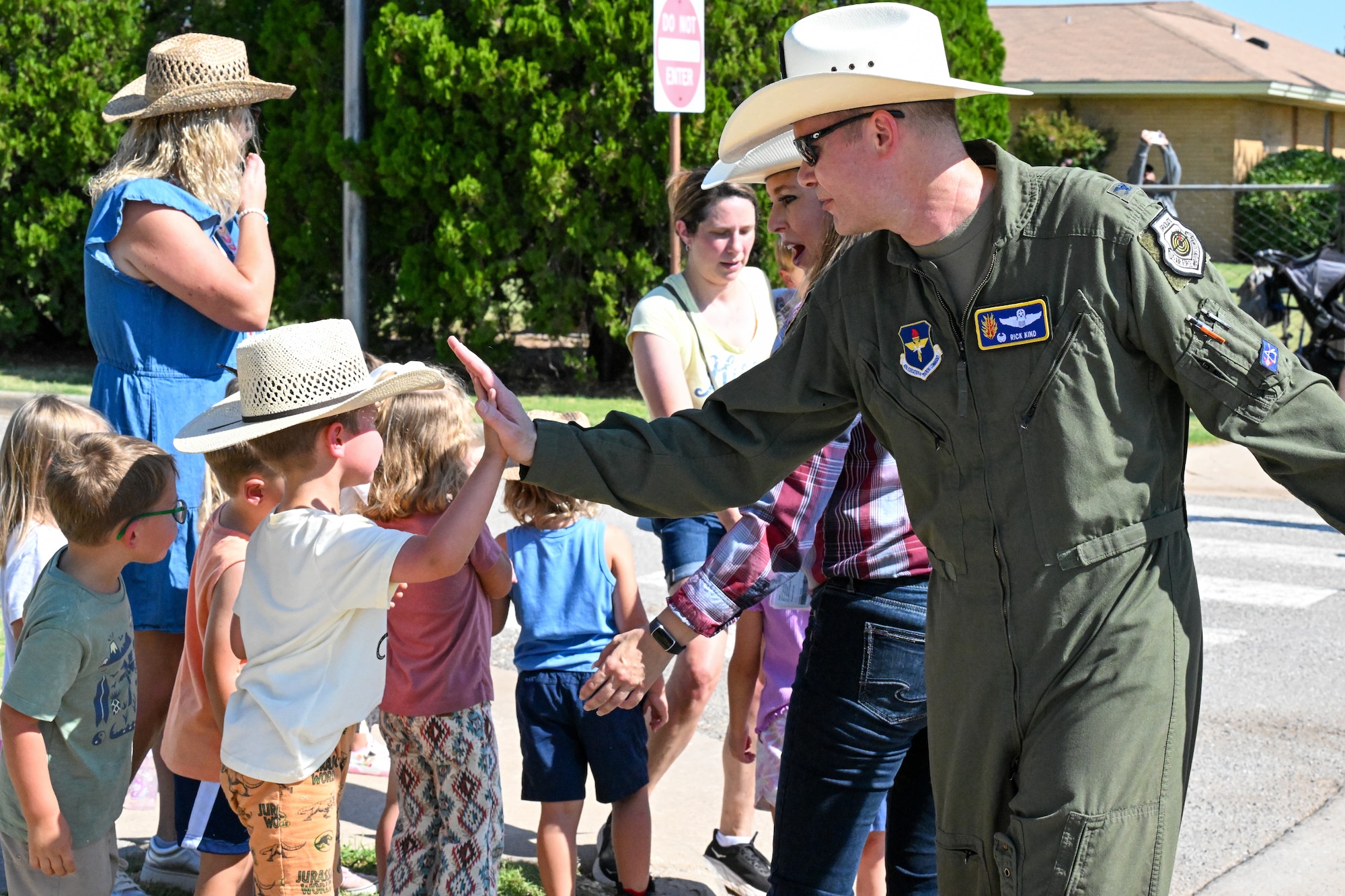 Col. Richard Kind, 97th Air Mobility Wing commander, high fives local school children at the 2025 Cattle Drive at Altus Air Force Base (AFB), Oklahoma, Aug. 21, 2025. Spectators from all across Altus AFB came out to the streets to witness the longhorn cattle graze through the base. (U.S. Air Force photo by Airman 1st Class Nathan Langston)