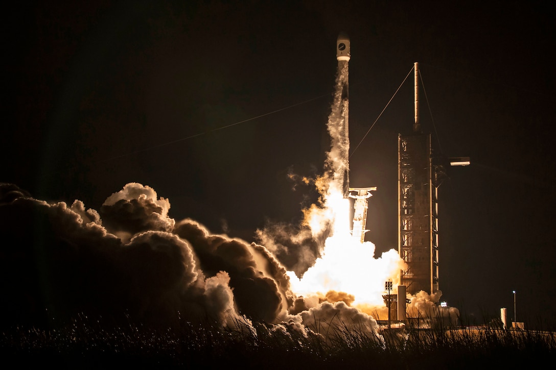 A rocket launches from a platform and sends smoke and bright light out from it.