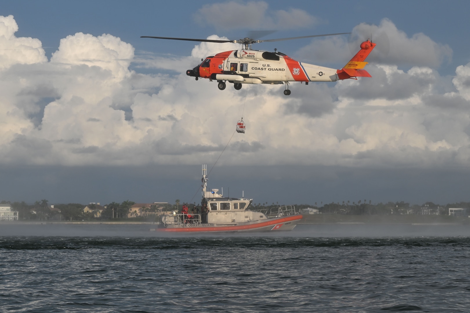 A U.S. Coast Guard Air Station Clearwater MH-60 Jayhawk aircrew deploys a rescue basket to a U.S. Coast Guard Station Sand Key 45-foot response boat-medium boat crew in Sand Key, Florida, Aug. 13, 2025. U.S. Coast Guard Sector St. Petersburg aircrews and boat crews regularly conduct rescue basket hoist training to maintain operational readiness. (U.S. Coast Guard photo by Petty Officer 1st Class Riley Perkofski)