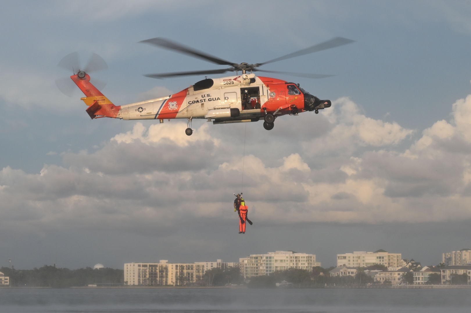 Petty Officer 2nd Class Zachary Loesch, a rescue swimmer assigned to U.S. Coast Guard Air Station Clearwater, conducts a sling hoist with a rescue dummy into a hovering MH-60 Jayhawk during search and rescue training in Sand Key, Florida, Aug. 13, 2025. U.S. Coast Guard Air Station Clearwater has an area of responsibility that encompasses over 400 nautical miles of coastline along the west coast of Florida. (U.S. Coast Guard photo by Petty Officer 1st Class Riley Perkofski)