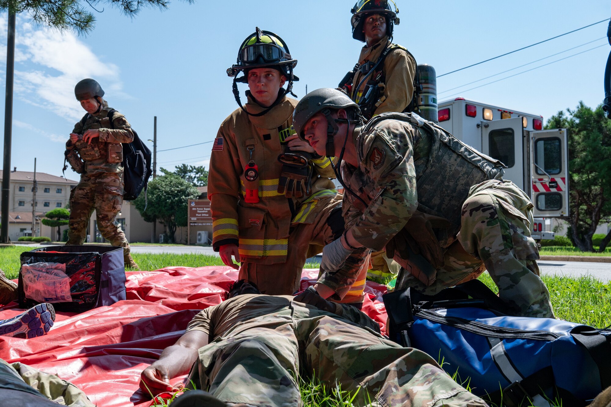 A combat medic tends to someone next to a firefighter