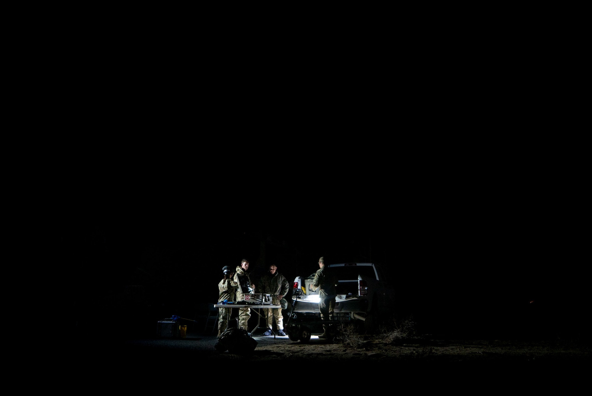 A site camp is illuminated by floodlights against the darkness surrounding 386th ECES Airmen in the dead of night