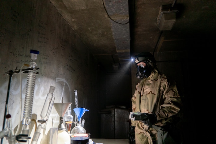 A 386th ECES Airman on the righthand side of frame illuminates a simulated chemical site using his headlamp