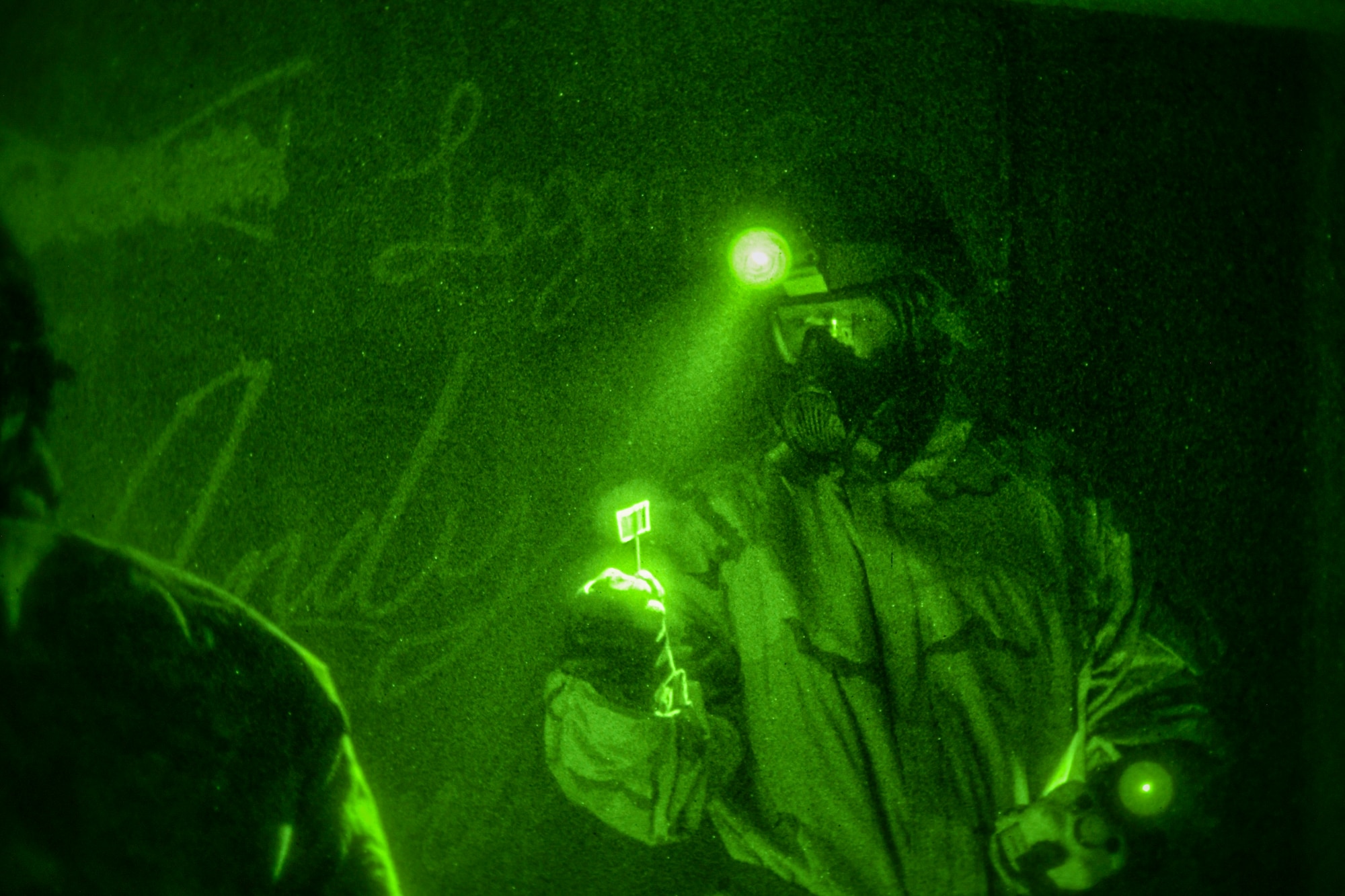 A 386th ECES Airman holds a device used for detecting chemicals as their headlamp shines on it