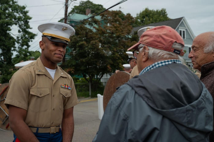 U.S. Marine Corps 1st Lt. Shonquez Caldwell a logistics officer with the Special Purpose Marine Air-Ground Task Force-250 speaks with Louis Cappuccio, son of U.S. Marine Corps Cpl. Joseph J. Cappuccio, who served in the Battle of Iwo Jima, at a WWII dedication during Marine Week Boston 2025, Aug. 21, 2025. Joseph J. Cappuccio Square was renamed in honor of Cpl. Cappuccio’s service. As the Marine Corps marks its 250th year, Marines worldwide observe this historic milestone, paying tribute to generations of valor, duty, and the enduring spirit of Semper Fidelis. (U.S. Marine Corps photo by Lance Cpl. Matthew A. McDonnell)
