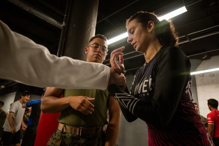 U.S. Marine Corps Sgt. Christian Alfaro, a native of Wayland, Mass., and a logistics specialist assigned to Special Purpose Marine Air-Ground Task Force-250, watches a Jiu-Jitsu technique during a martial arts collaboration at Broadway Jiu-Jitsu during Marine Week Boston, Aug. 22, 2025. Marines stationed across the globe commemorate the 250th anniversary of the Marine Corps, honoring a distinguished legacy of service, sacrifice, and unwavering fidelity to both the nation and fellow Marines. (U.S. Marine Corps photo by Cpl. Vincent Needham)
