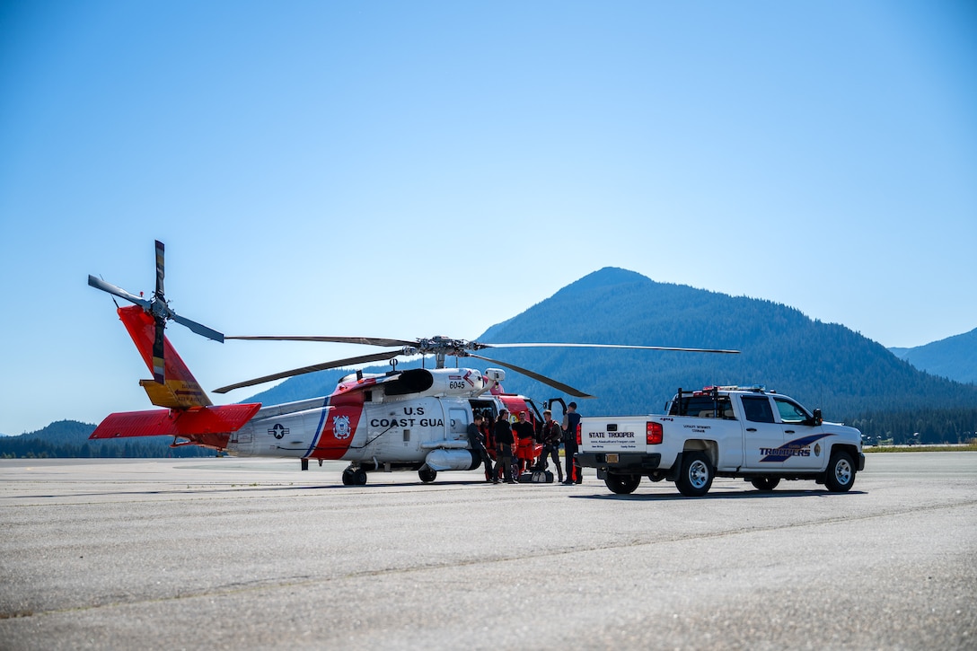 A Coast Guard MH-60 Jayhawk helicopter aircrew from Coast Guard Air Station Sitka stands near their helicopter in Juneau, Alaska, after rescuing a pilot from a downed aircraft Aug. 24, 2025. The pilot was the only person aboard the downed aircraft and had no reported injuries. (U.S. Coast Guard photo by Chief Petty Officer Travis Magee)