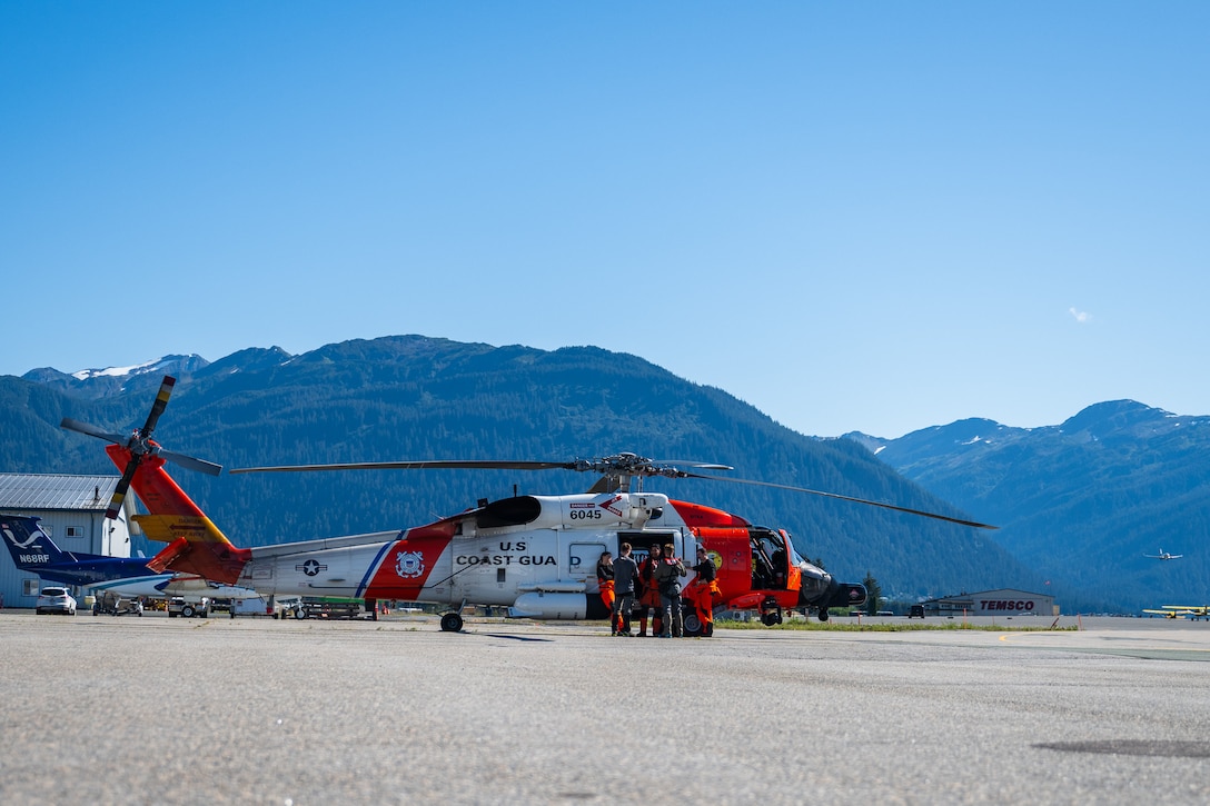 A Coast Guard MH-60 Jayhawk helicopter aircrew from Coast Guard Air Station Sitka stands near their helicopter in Juneau, Alaska, after rescuing a pilot from a downed aircraft Aug. 24, 2025. The pilot was the only person aboard the downed aircraft and had no reported injuries. (U.S. Coast Guard photo by Chief Petty Officer Travis Magee)