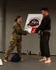 U.S. Marine Corps 1st Lt. Hope Nelson, a planning officer assigned to Special Purpose Marine Air-Ground Task Force-250, gives a gift to John Clarke, owner of Broadway Jiu-Jitsu, after a martial arts collaboration at Broadway Jiu-Jitsu during Marine Week Boston, Aug. 22, 2025. Marines stationed across the globe commemorate the 250th anniversary of the Marine Corps, honoring a distinguished legacy of service, sacrifice, and unwavering fidelity to both the nation and fellow Marines. (U.S. Marine Corps photo by Cpl. Vincent Needham)