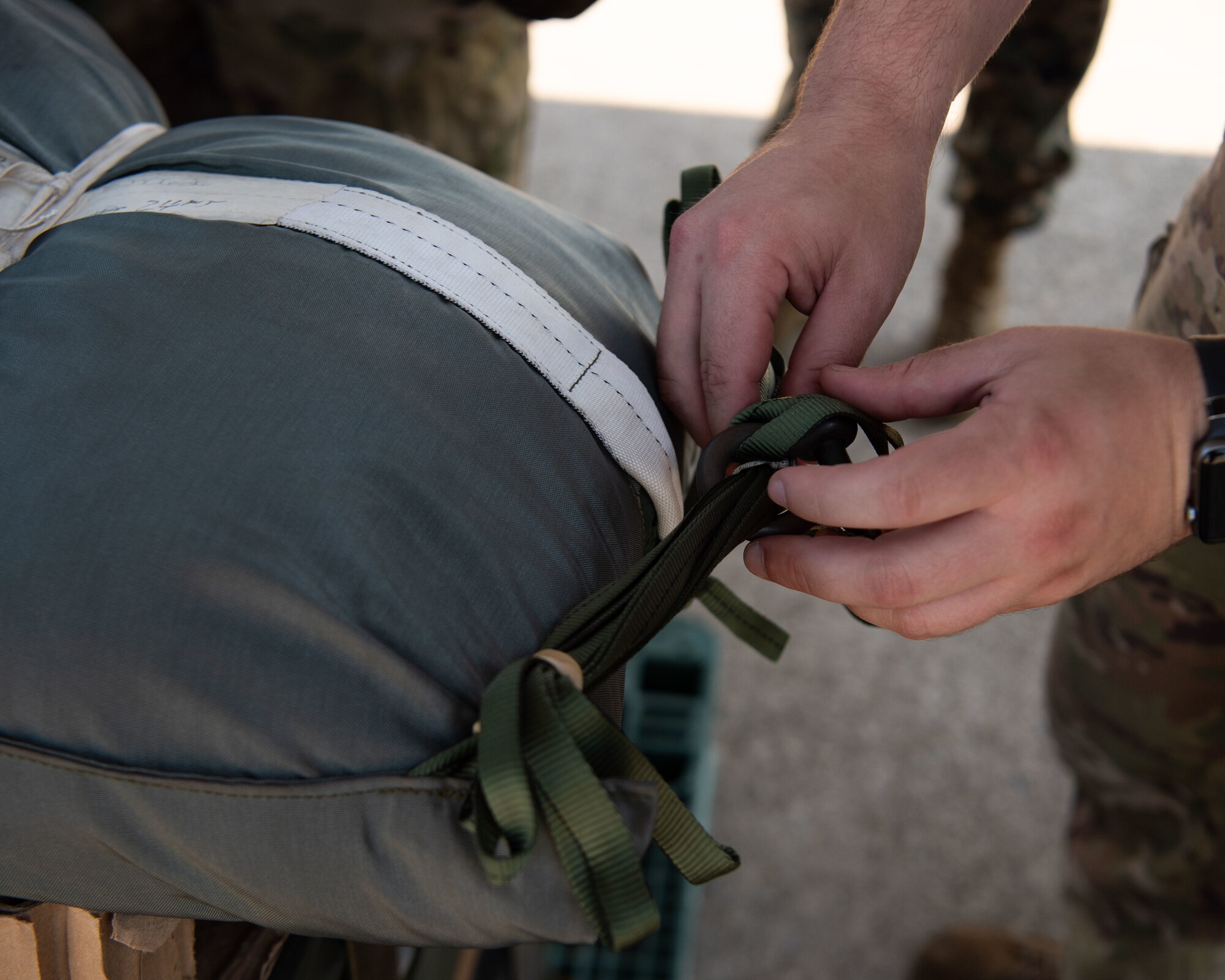 A U.S. servicemembers ensures a parachute pack is properly attached to cargo