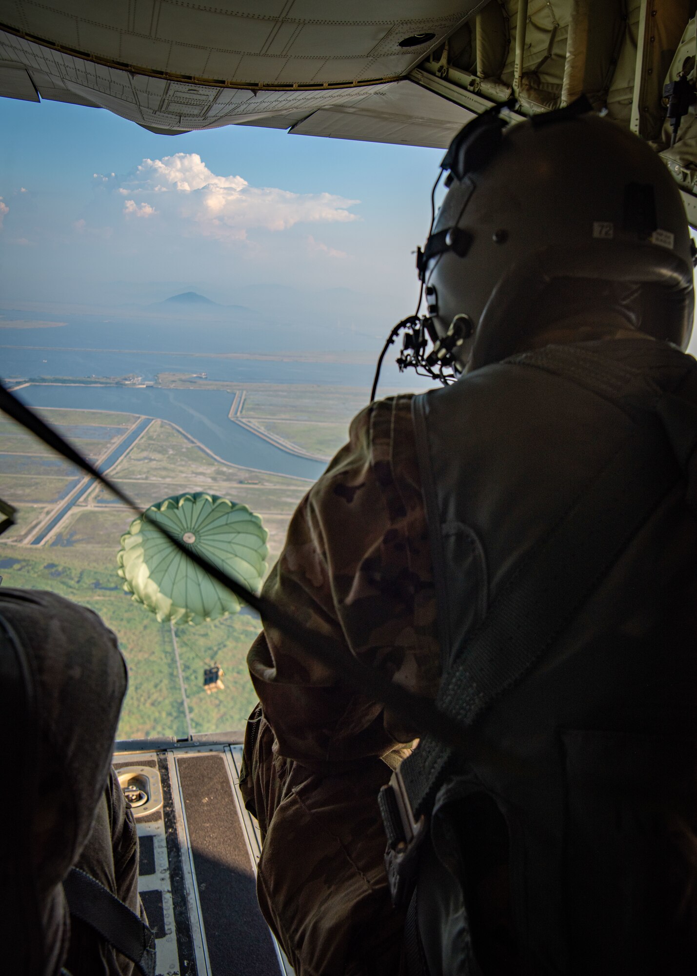 A U.S. servicemember watches a pallet fall out of the back of an aircraft