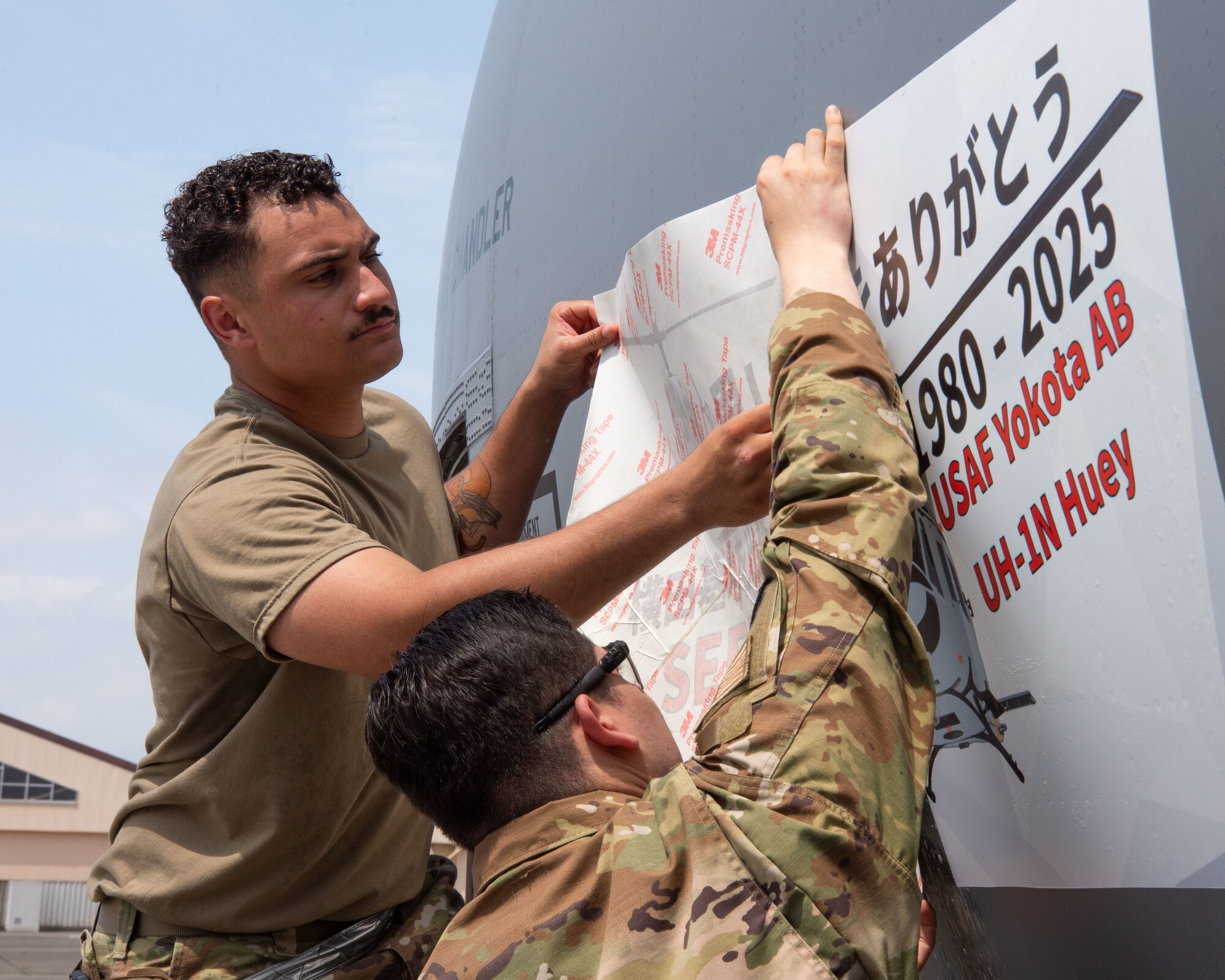 U.S. servicemembers apply a decal to the side of an aircraft