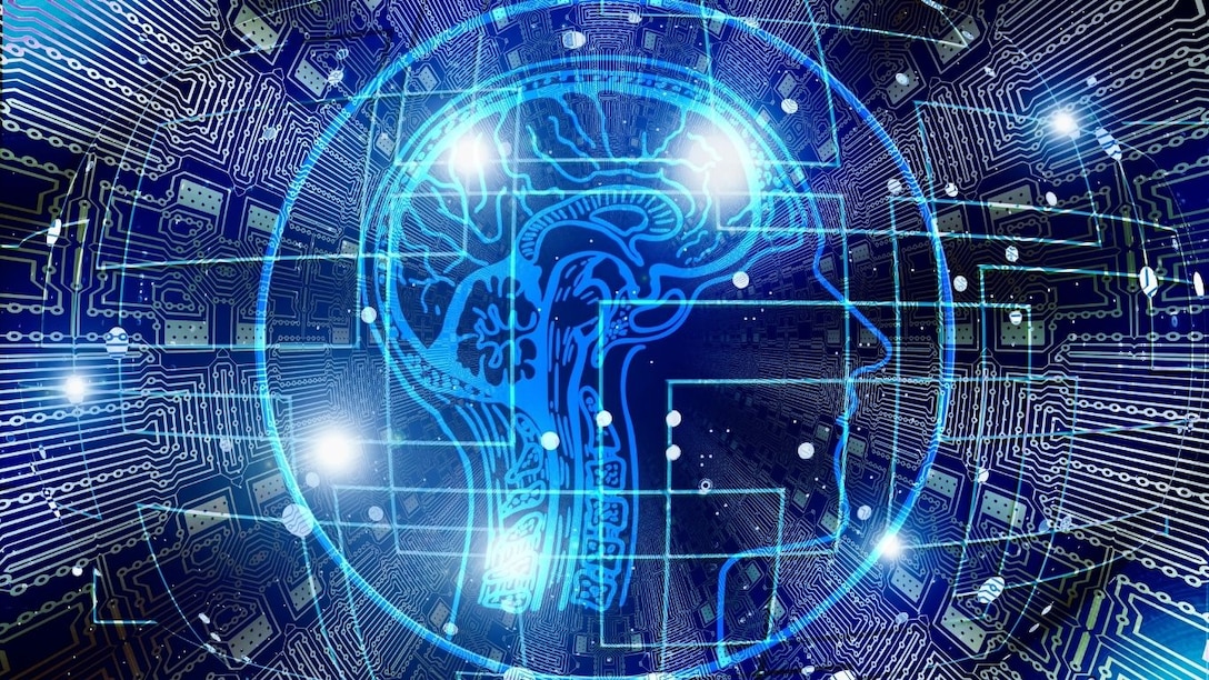 Digital illustration of a human head profile with a glowing brain composed of circuitry, overlaid on a digital background of electronic circuits, symbolizing artificial intelligence and the fusion of technology with the human mind.