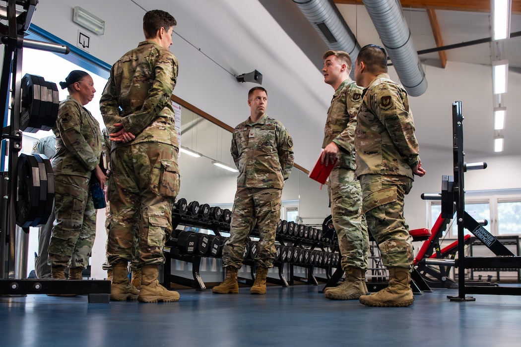 Airmen stand in a circle and talk in a gym