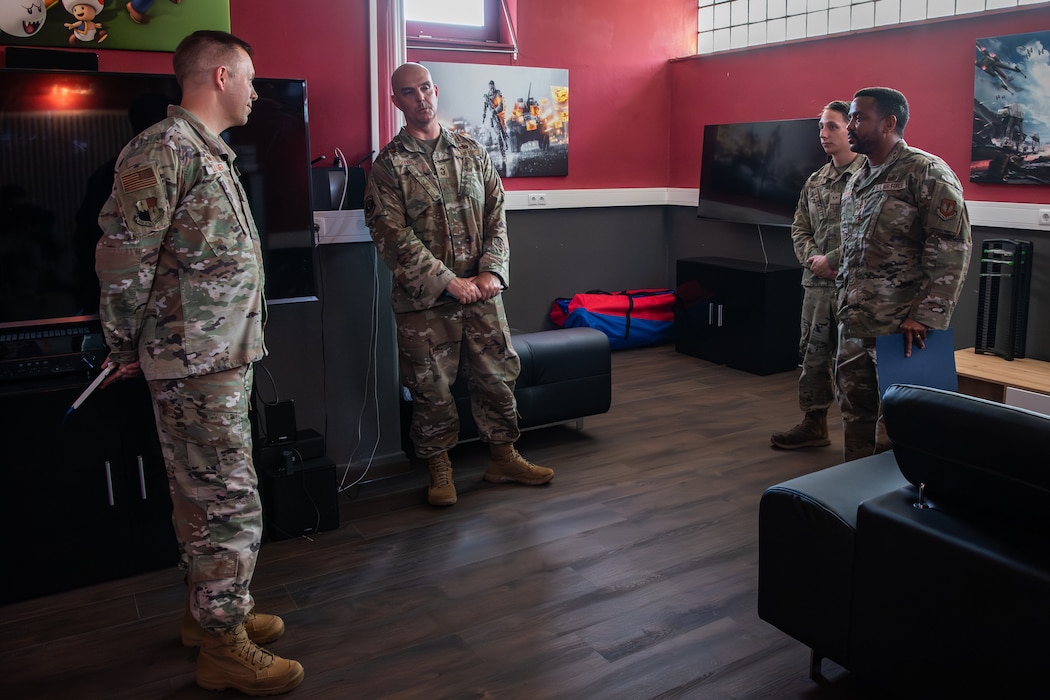 A group of U.S. Airmen stand in a circle in a game room.