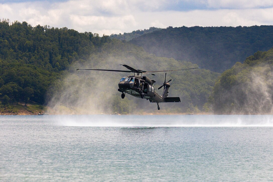 A helicopter hovers above a lake.