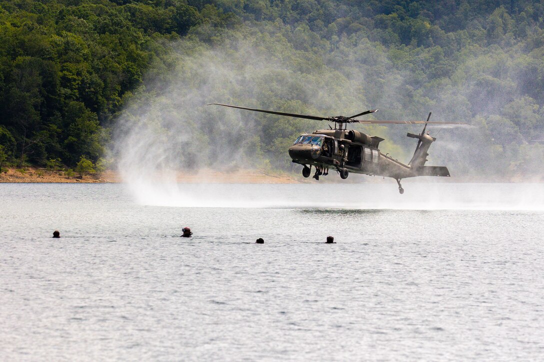 A helicopter hovers above a lake.