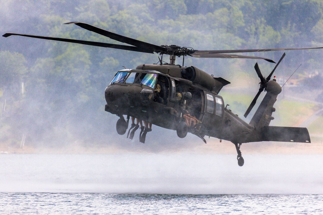 A helicopter hovers above a lake.
