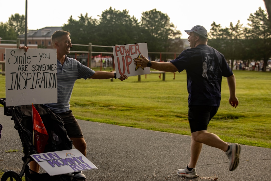 A bystander encourages a runner during the Quantico 12K on Marine Corps Base Quantico, Virginia, Aug. 23, 2025. The event challenges runners and their individual tenacity as they ran 7.46 miles of trails through the woods of Marine Corps Base Quantico's Officer Candidate School. (U.S. Marine Corps photo by Lance Cpl. Federico Marquez)