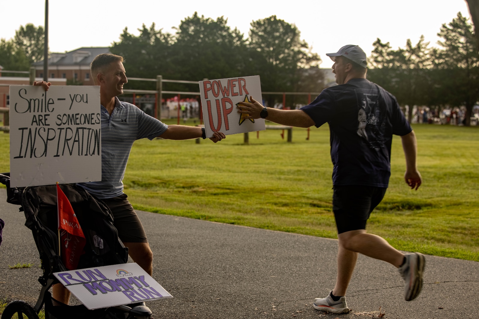 A bystander encourages a runner during the Quantico 12K on Marine Corps Base Quantico, Virginia, Aug. 23, 2025. The event challenges runners and their individual tenacity as they ran 7.46 miles of trails through the woods of Marine Corps Base Quantico's Officer Candidate School. (U.S. Marine Corps photo by Lance Cpl. Federico Marquez)