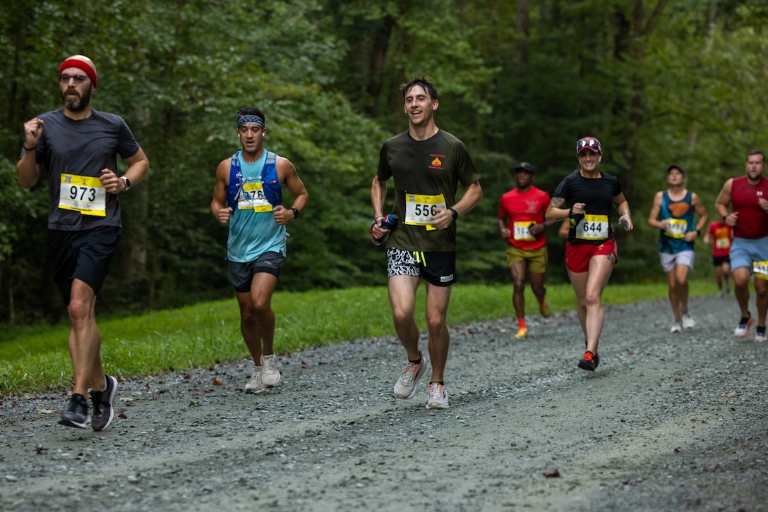 Participants run in the Quantico 12K on Marine Corps Base Quantico, Virginia, Aug. 23, 2025. The event challenges runners and their individual tenacity as they ran 7.46 miles of trails through the woods of Marine Corps Base Quantico's Officer Candidate School. (U.S. Marine Corps photo by Lance Cpl. Federico Marquez)