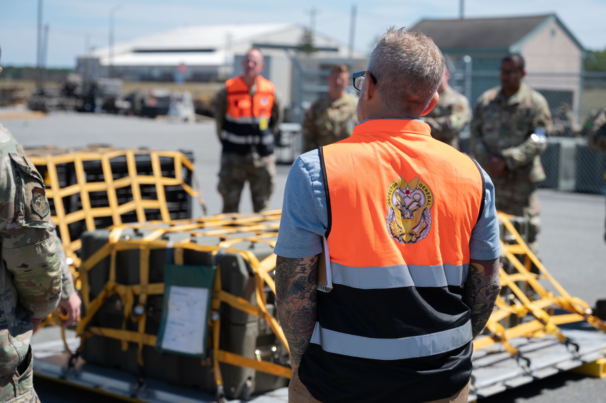 Inspector watches Airmen secure cargo.