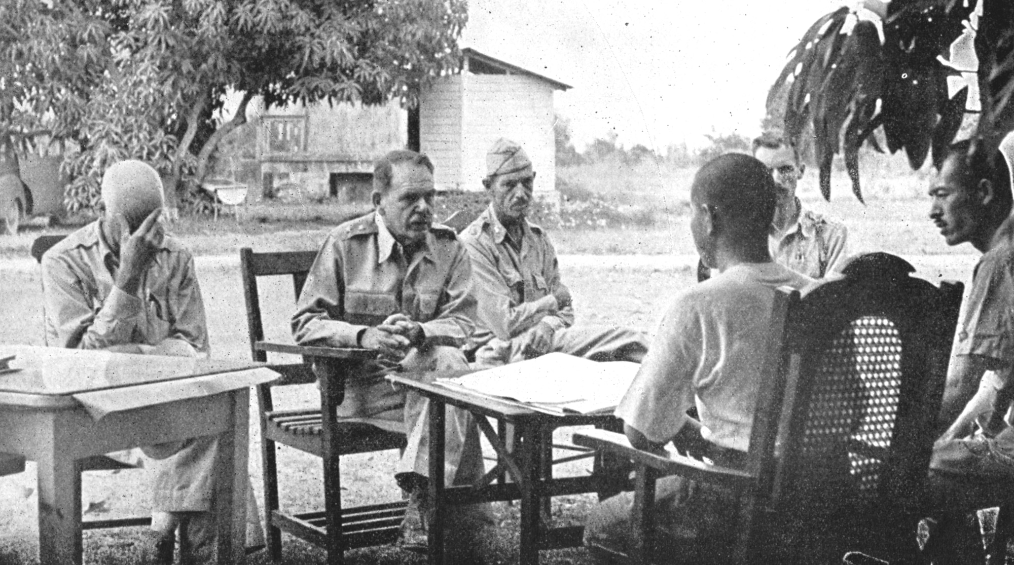 Americans discussing surrender terms with the Japanese representative, Col Nakayama. From left to right, Col Everett Williams, Maj Gen Edward King, Jr., Maj Wade Cothran, and Maj Achille Tisdelle.