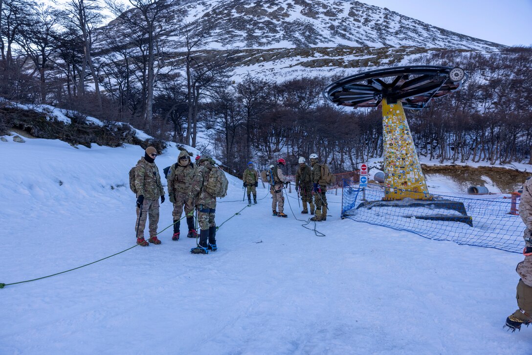 U.S. Marines from the Mountain Warfare Training Center and 8th Engineering Support Battalion, 2nd Marine Logistics Group, tie into ropes before a hike up to the peak of a mountain with Argentinian marines from Batallón de Infantería de Marina 4 and 5, in Ushuaia, Argentina, Aug 13, 2025. This training creates opportunities for continued combined exercises with Argentine forces which aims to build upon the skills learned in these knowledge exchanges. (U.S. Marine Corps photo by Lance Cpl. Payton Goodrich)