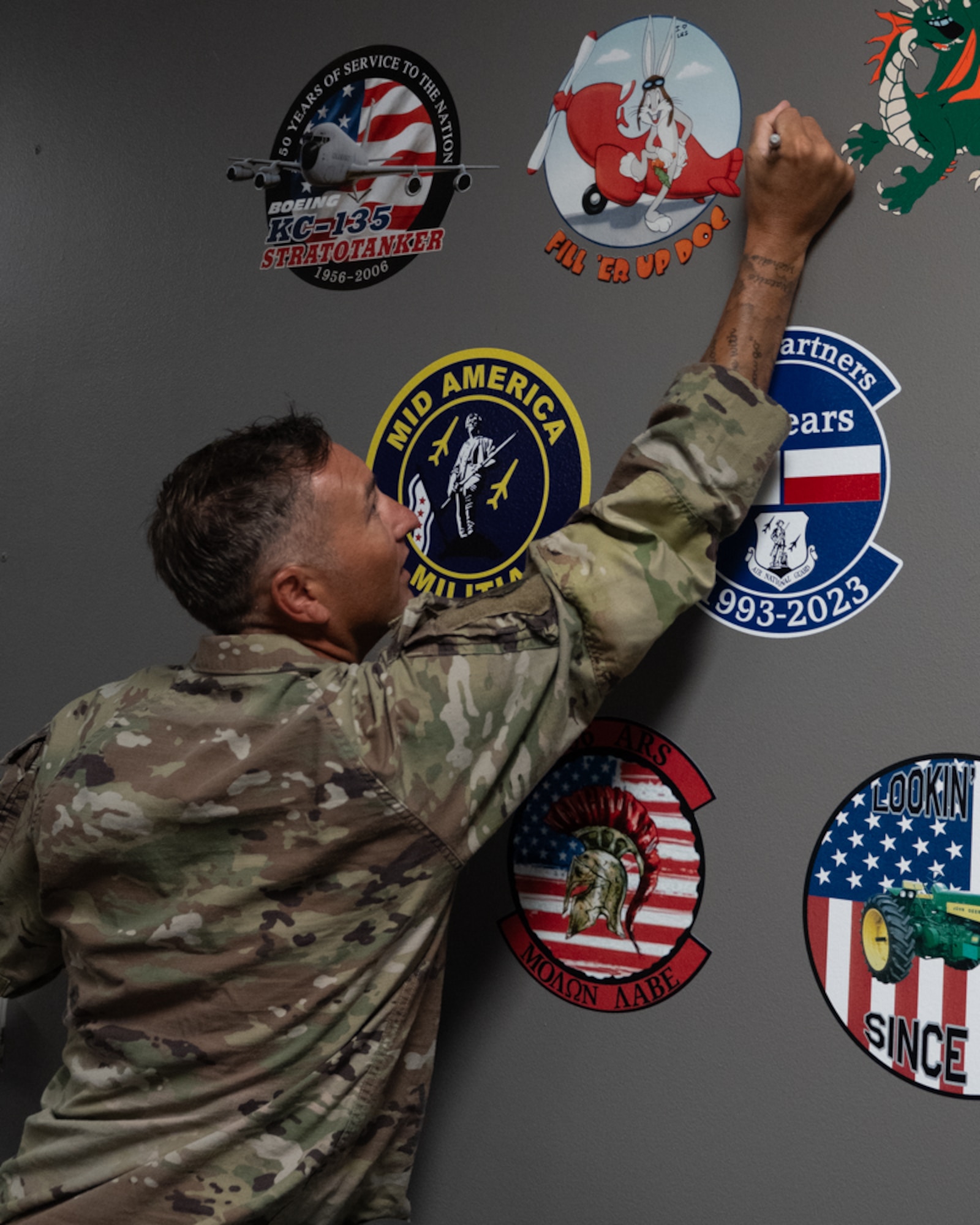 an airman signing his name next to the fill 'er up doc bugs bunny nose art on an aircraft gray wall.