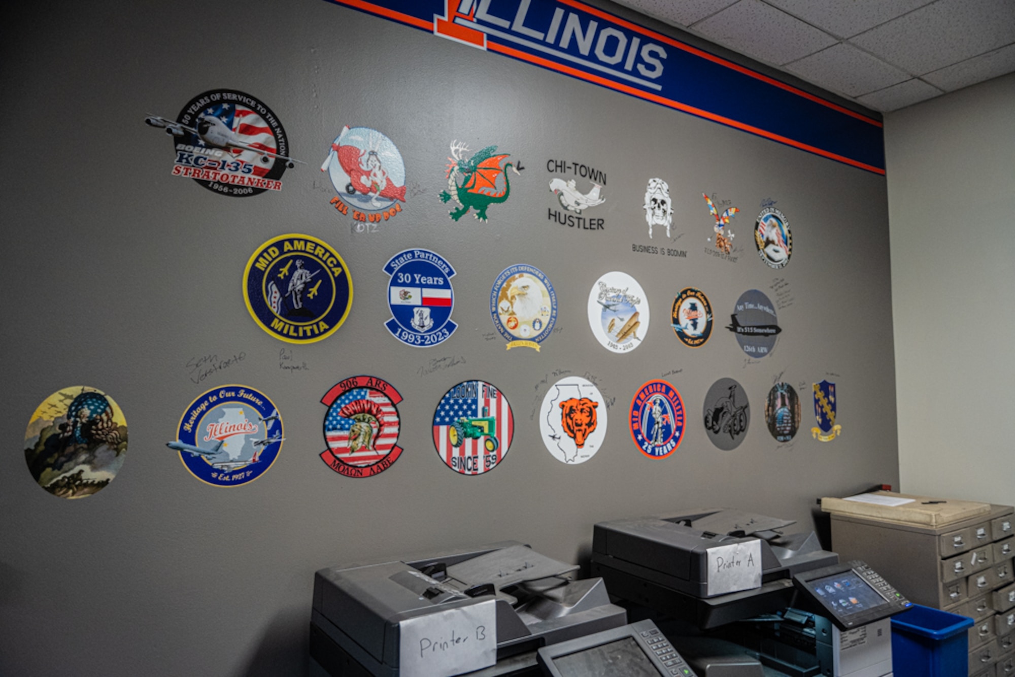 A gray wall with nose art and signatures.