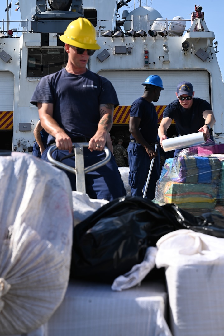 The crew of U.S. Coast Guard Cutter Hamilton (WMSL 753) moving illicit drugs on the flight deck on August 25, 2025, at Port Everglades, Florida. The drugs were transferred to partners such as the Drug Enforcement Agency for processing and destruction. (U.S. Coast Guard photo by Petty Officer 3rd Class Nicholas Strasburg)