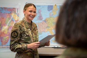 Staff Sgt. Eleanor Warren smiles, holding papers with maps in background
