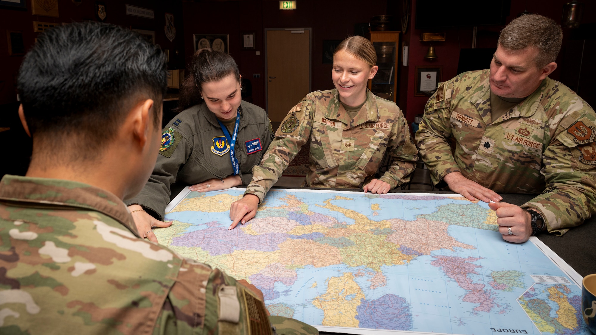 Staff Sgt. Eleanor Warren points to a location on a map while three Airmen observe.