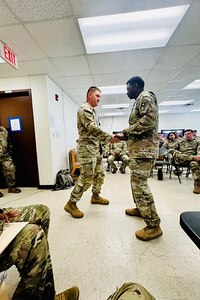 Command Sgt. Maj. Keyon D. Cummings, right, Command Seargent Major, 120th Infantry Brigade, First Army, presents Sgt. 1st Class Jason Blair, 2-382nd Logistics Support Battalion, “Mustangs”, 85th U.S. Army Reserve Support Command, with the 120th INF BDE Unit Crest coin for his exceptional leadership, coaching, and mentorship that enhanced operational readiness across the formation.