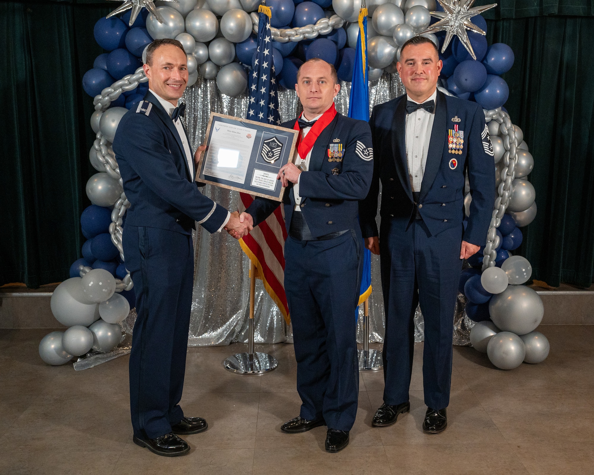 U.S. Air Force Col. Tyler Ellison, 47th Flying Training Wing (FTW) commander, left, and Chief Master Sgt. Erik Garza, 47th FTW command chief, right, present Technical Sgt. Robert Short, 47th Security Forces Squadron, center, with the Certificate of Induction at Laughlin Air Force Base, Texas, Aug. 22, 2025. The induction ceremony brings Airmen together to celebrate the achievement of entering the realm of senior enlisted leaders. (U.S. Air Force photo by Staff Sgt. Nicholas Larsen)