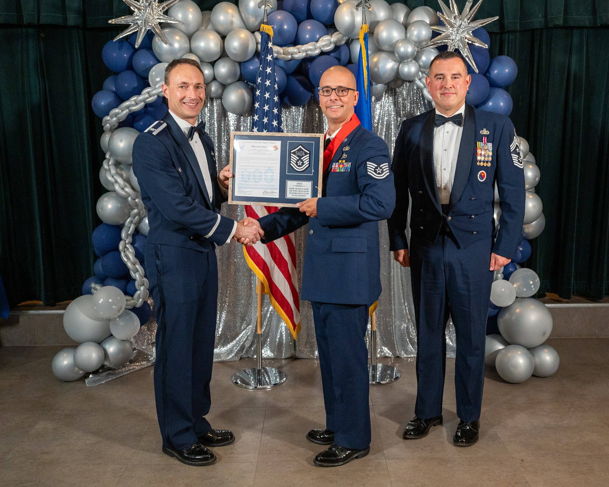 U.S. Air Force Col. Tyler Ellison, 47th Flying Training Wing (FTW) commander, left, and Chief Master Sgt. Erik Garza, 47th FTW command chief, right, present Technical Sgt. Joshua Olando, 47th Force Support Squadron, center, with the Certificate of Induction at Laughlin Air Force Base, Texas, Aug. 22, 2025. The induction ceremony brings Airmen together to celebrate the achievement of entering the realm of senior enlisted leaders. (U.S. Air Force photo by Staff Sgt. Nicholas Larsen)