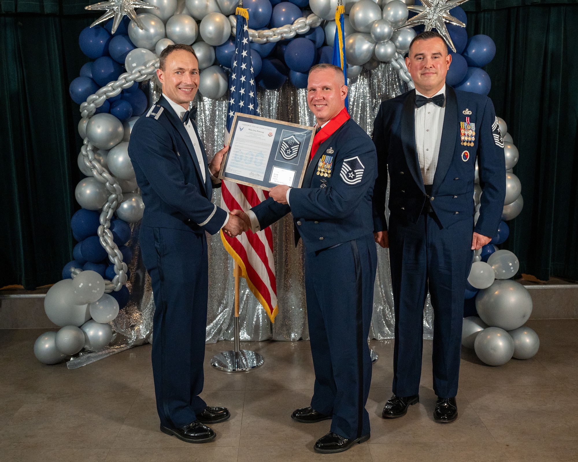 U.S. Air Force Col. Tyler Ellison, 47th Flying Training Wing (FTW) commander, left, and Chief Master Sgt. Erik Garza, 47th FTW command chief, right, present Master Sgt. Casey Blickenstaff, 47th Security Forces Squadron, center, with the Certificate of Induction at Laughlin Air Force Base, Texas, Aug. 22, 2025. The induction ceremony brings Airmen together to celebrate the achievement of entering the realm of senior enlisted leaders. (U.S. Air Force photo by Staff Sgt. Nicholas Larsen)