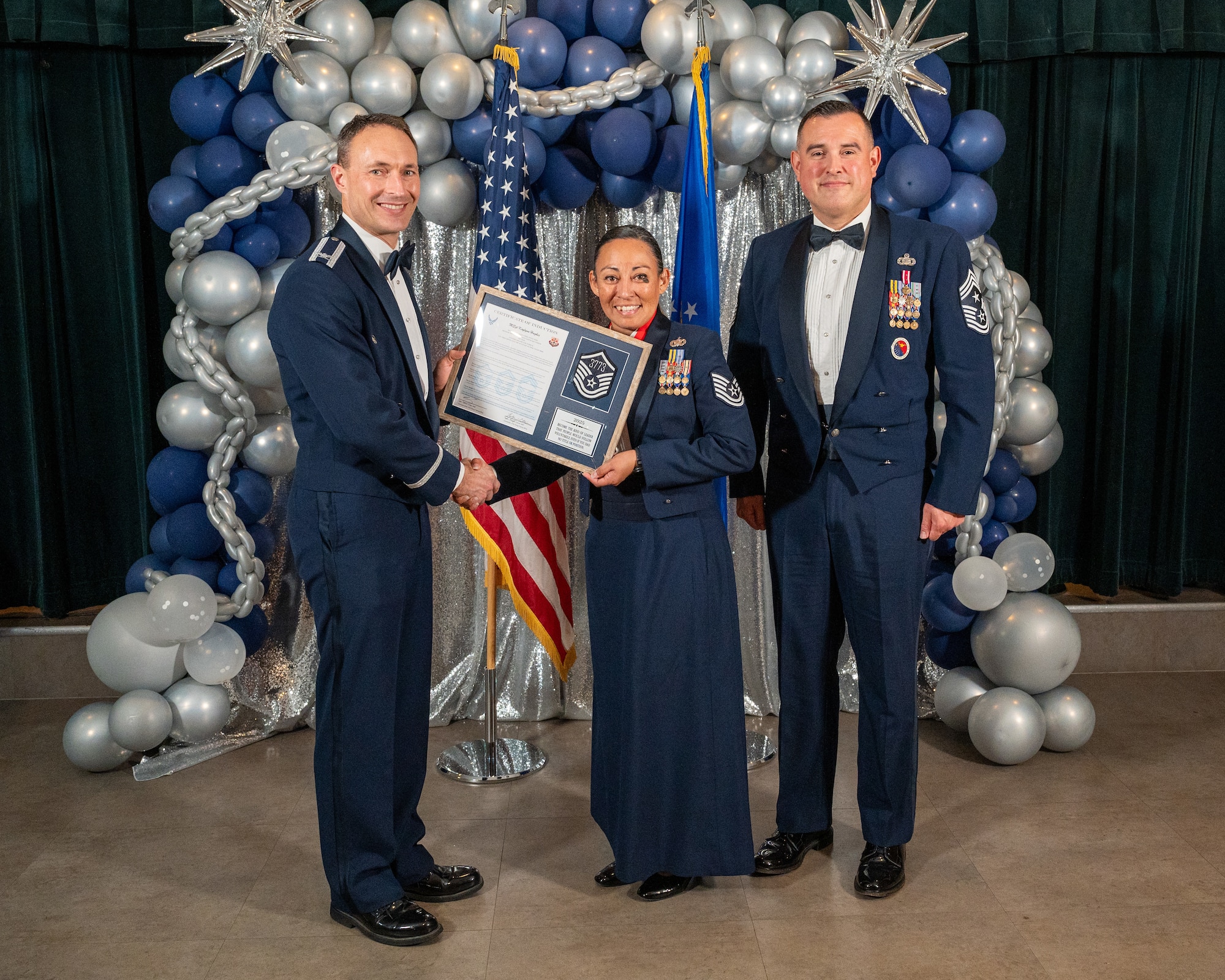 U.S. Air Force Col. Tyler Ellison, 47th Flying Training Wing (FTW) commander, left, and Chief Master Sgt. Erik Garza, 47th FTW command chief, right, present Technical Sgt. Kaylynn Hughes, 47th Security Forces Squadron, center, with the Certificate of Induction at Laughlin Air Force Base, Texas, Aug. 22, 2025. The induction ceremony brings Airmen together to celebrate the achievement of entering the realm of senior enlisted leaders. (U.S. Air Force photo by Staff Sgt. Nicholas Larsen)