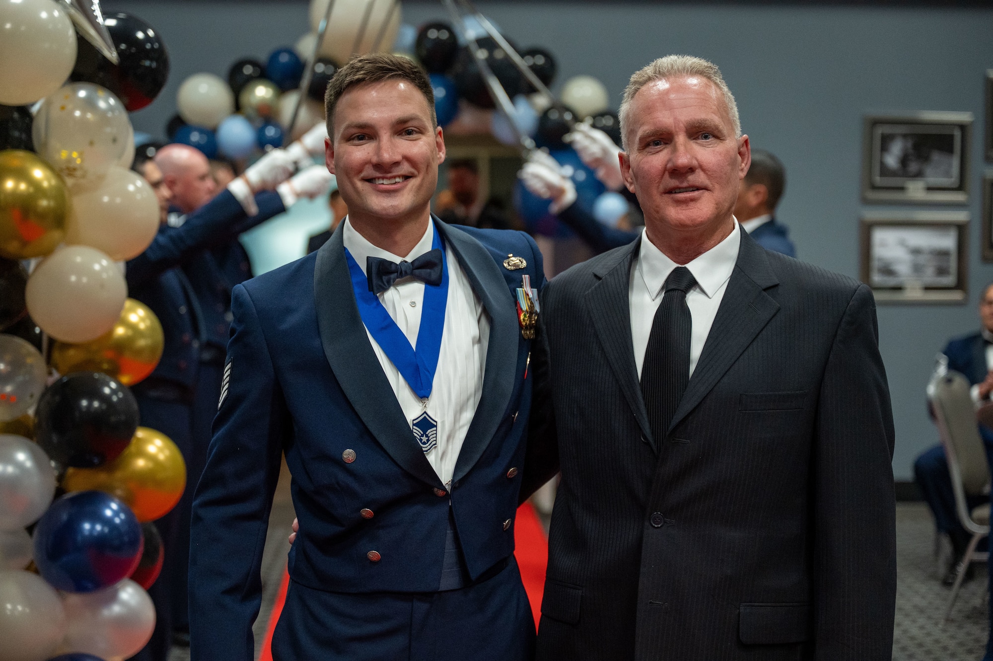 U.S. Air Force Tech. Sgt. John Meadows III, 315th Training Squadron, accompanied by his dad, John Meadows II, walk through the saber cordon, inducting him into the highest tier of the enlisted force during the Senior Noncommissioned Officer Induction Ceremony at the Powell Event Center, Goodfellow Air Force Base, Texas, Aug. 22, 2025. Each inductee entered the room through a saber cordon, which is used to salute the new SNCOs as a show of respect for the sacrifices and commitments the inductees have made to earn the rank of master sergeant. (U.S. Air Force photo by Airman 1st Class James Salellas)
