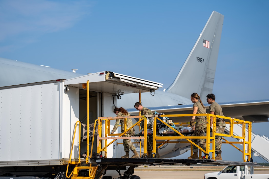Airmen from the 59th Medical Wing at Joint Base San Antonio, carry a medical simulation mannequin onto a KC-46 Pegasus aircraft at Kelly Field, San Antonio, Texas, Aug. 21, 2025. The mannequin was used to simulate a critically ill patient, giving aeromedical evacuation and critical care air transport teams the opportunity to practice patient movement and in-flight care procedures during the “Vapor Trails” exercise.  (U.S. Air Force photo by Airman 1st Class Lauren Torres)