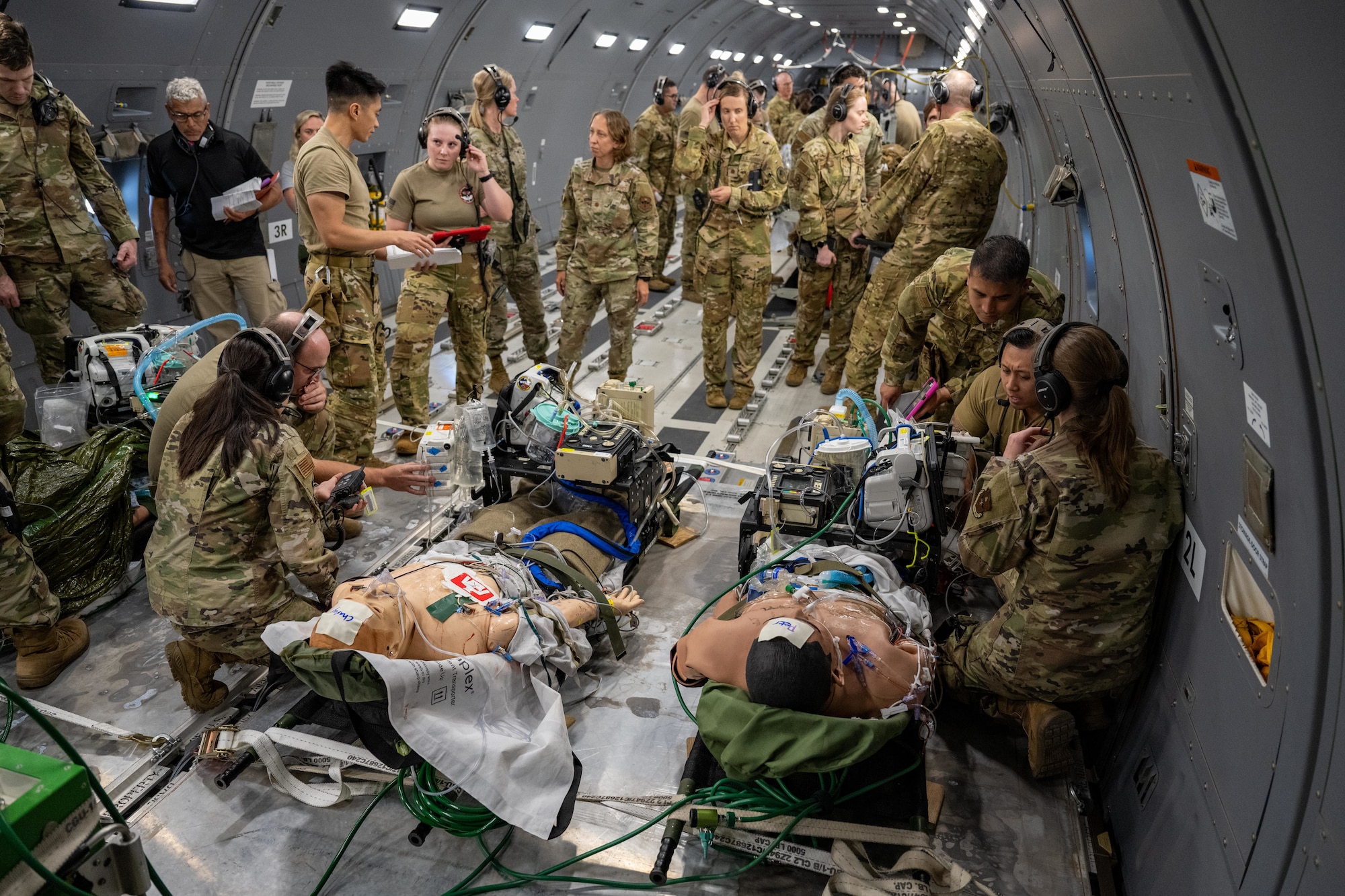 Airmen gather around medical simulation mannequins on a KC-46 Pegasus aircraft during “Vapor Trails” at Kelly Airfield, San Antonio, Texas, Aug. 21, 2025. The aircraft’s reconfigurable design allowed aeromedical evacuation and critical care air transport teams to practice loading patients, operating medical equipment, and coordinating care in-flight. (U.S. Air Force photo by Airman 1st Class Lauren Torres)