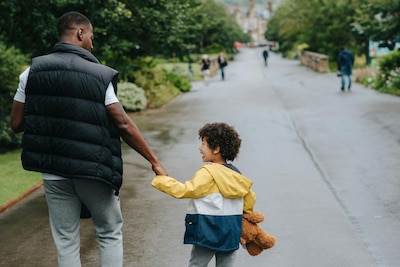 Father and son hold hands while walking down a street