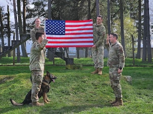 a man salutes another man with a dog sitting next to him