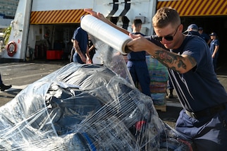 A U.S. Coast Guard Cutter Hamilton (WMSL 753) crew member plastic wrapping drugs during an offload of approximately 76,140 lbs of illicit narcotics at Port Everglades, Florida, on August 25, 2025. This offload was the result of 19 separate interdictions in the Eastern Pacific Ocean and the Caribbean. (U.S. Coast Guard photo by Petty Officer 3rd Class Nicholas Strasburg)