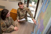 Staff Sgt. Eleanor Warren points to a location on a map with another Airman watching