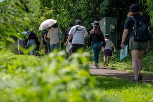 Local residents walk a trail to a former hospital cave during a historical site tour of Kadena Air Base, Japan, Aug. 13, 2025.
