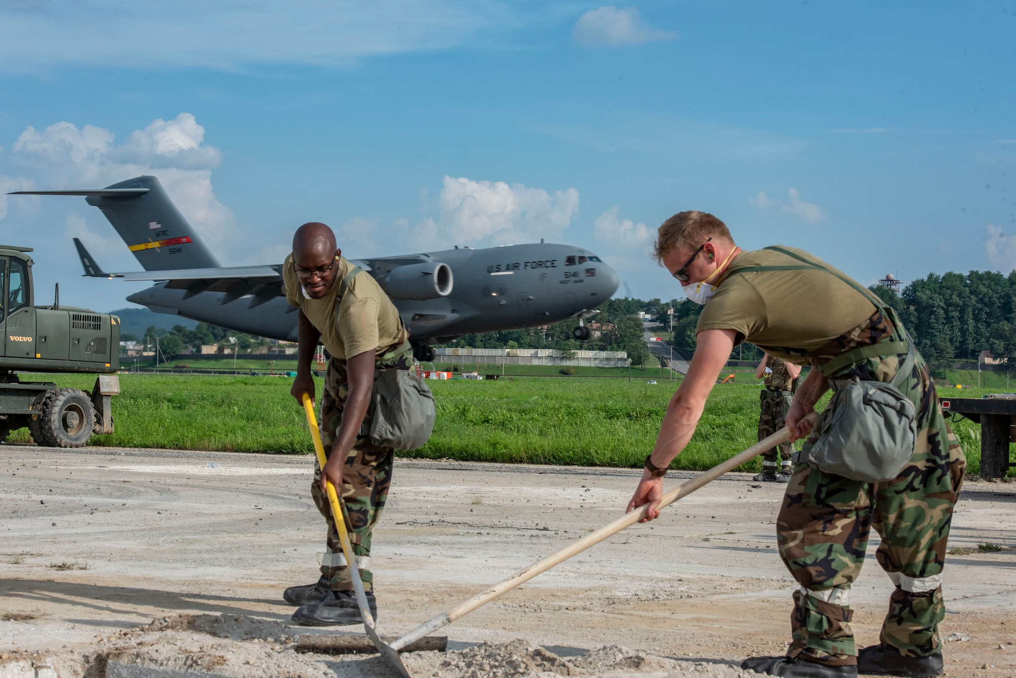 U.S. Air Force Staff Sgt. Connor Stevens, left, 51st Civil Engineer Squadron structural engineer, and Staff Sgt. Hayden Brooks, 51st CES structural engineer, conduct rapid airfield damage repair while a C-17 Globemaster III lands during exercise Ulchi Freedom Shield 25 at Osan Air Base, Republic of Korea, Aug. 20, 2025